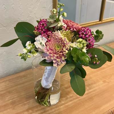 Hand-tied bouquet of pink and white flowers in a clear glass vase