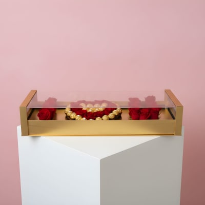 Red roses arranged in a gold box with a clear lid