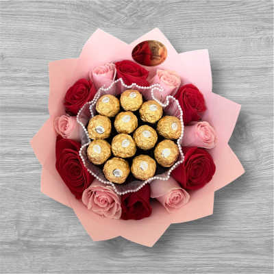 Pink and red roses arranged around gold-wrapped chocolates