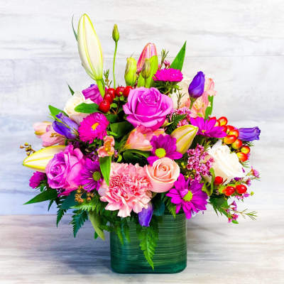 Colorful mixed flower arrangement in a green glass vase