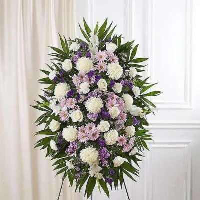Standing funeral spray with white, pink, and purple flowers on an easel