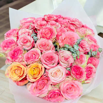 Large bouquet of pink and peach roses wrapped in white paper