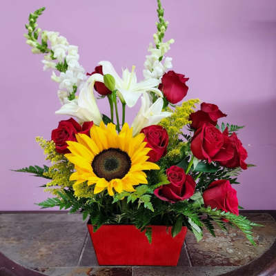 Sunflower and red rose arrangement in a red container