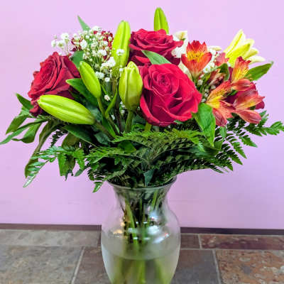 Bouquet of red roses and lilies in a clear glass vase