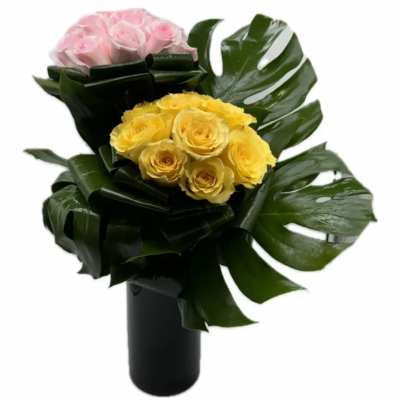 Bouquet of yellow and pink roses in a black vase with large tropical leaves