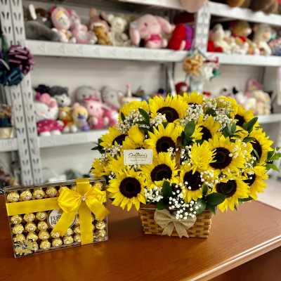 Sunflower arrangement in a wicker basket beside a box of chocolates