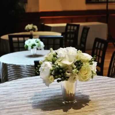 White and pale green floral centerpiece in a clear vase