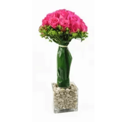 Pink rose bouquet in a tall glass vase with a stone-filled base