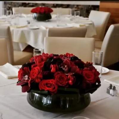 Red rose centerpiece in a low black vase on a white tablecloth