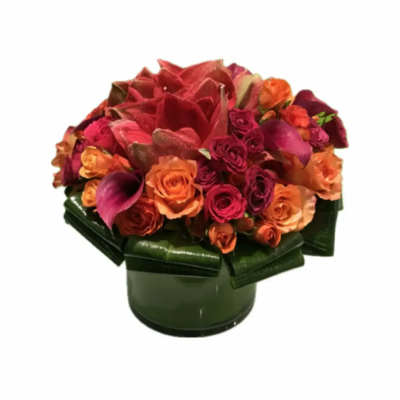 Mixed bouquet of red, orange, and pink flowers in a green vase