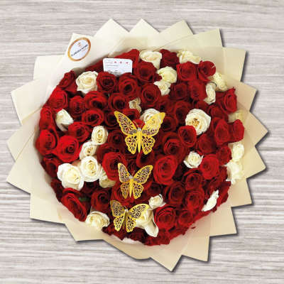 Heart-shaped bouquet of red and white roses with butterfly picks
