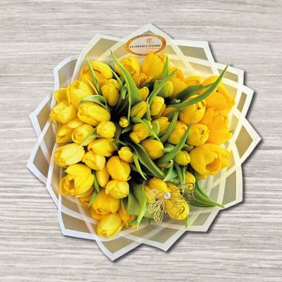 Bouquet of yellow tulips wrapped in layered paper