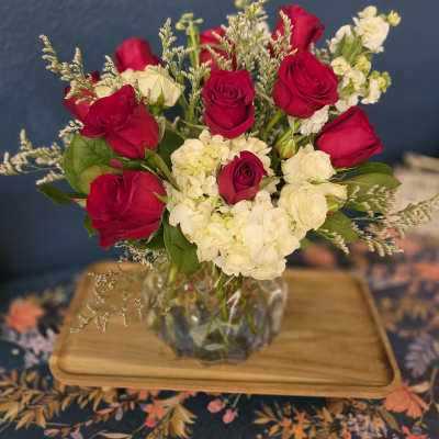 Red roses and white blooms arranged in a clear glass vase