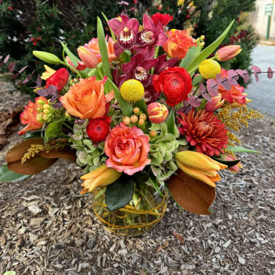 Colorful bouquet with orchids, roses, and tulips in a glass vase