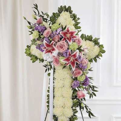 Standing floral cross with pink roses, lilies, and purple blooms