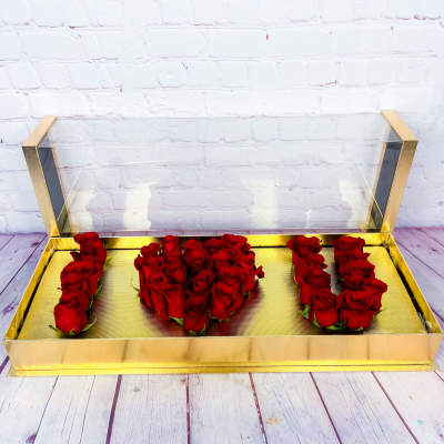 Red roses arranged in a gold box to spell "I U"