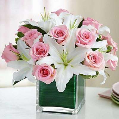 Pink roses and white lilies arranged in a square glass vase
