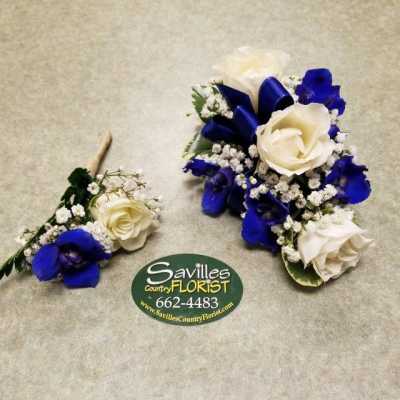 Two blue and white floral corsages with roses and baby's breath.