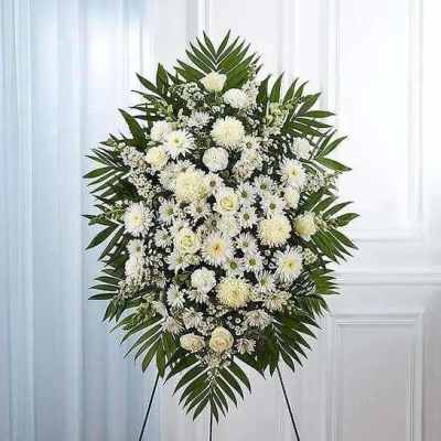 White funeral spray on an easel with palm fronds
