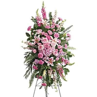 Tall pink standing spray with roses, lilies, and carnations on a black easel.
