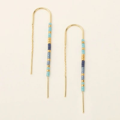 Pair of gold threader earrings with turquoise and blue beads on a light background