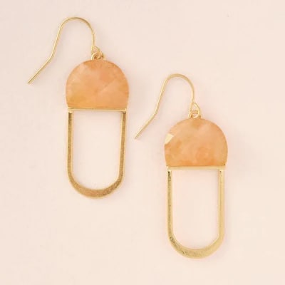Pair of gold dangle earrings with peach half-circle tops on a light background