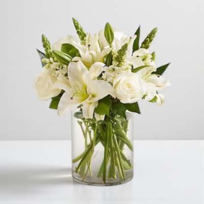 White lilies and roses arranged in a clear glass vase