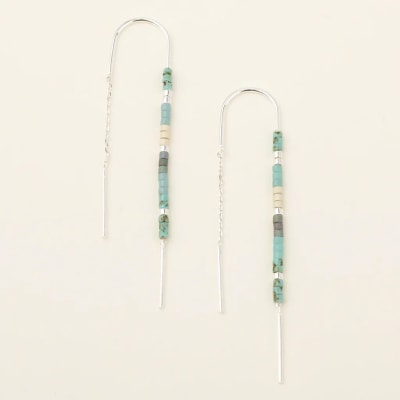Pair of long silver threader earrings with turquoise, gray, and cream beads on a light background
