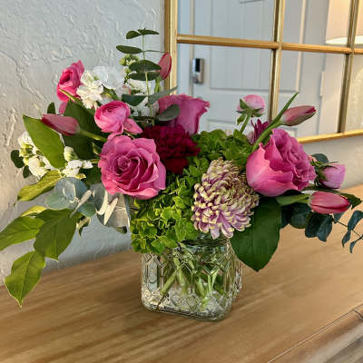 Pink roses and mixed blooms arranged in a clear glass vase