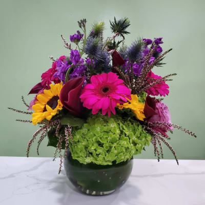 Bright mixed flower arrangement in a dark glass vase