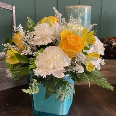 Yellow and white floral arrangement in a blue vase