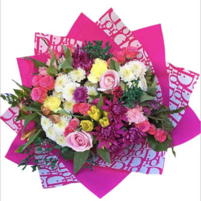 Bright mixed bouquet with pink, white, and yellow flowers wrapped in hot pink paper