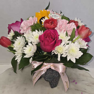 Mixed bouquet of roses, tulips, carnations, and white daisies in a vase