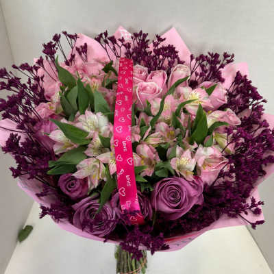 Bouquet of pink and purple flowers wrapped with a heart ribbon