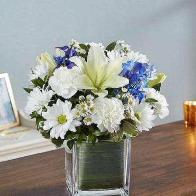 White and blue flower arrangement in a clear square vase
