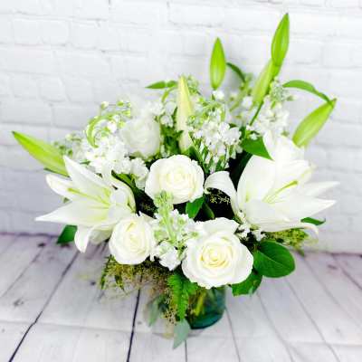 White lilies and roses arranged in a glass vase