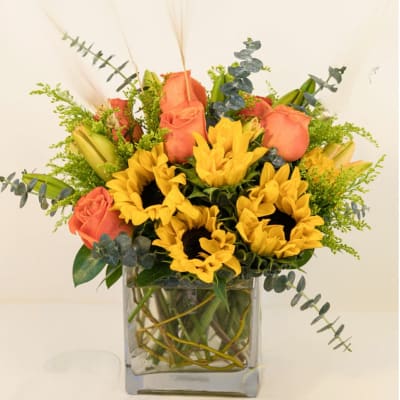 Sunflowers and peach roses in a square glass vase
