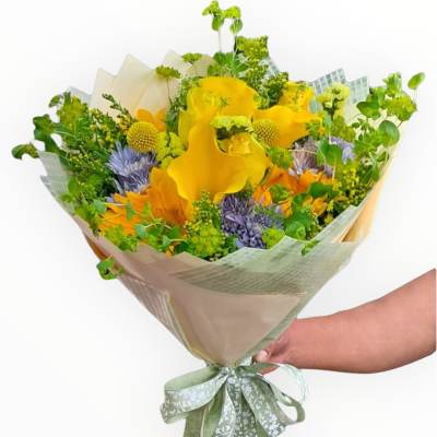 Hand-tied bouquet of yellow and purple flowers wrapped in pale paper