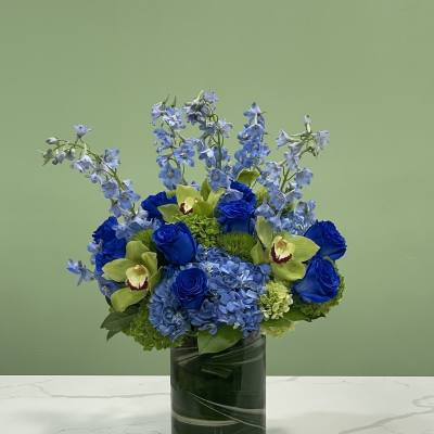 Blue and green floral arrangement in a glass vase