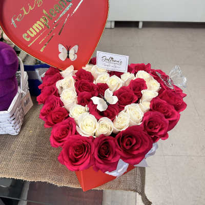 Heart-shaped rose arrangement with a red "Feliz cumpleaños" sign