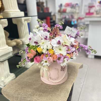 Pink and white floral arrangement in a round pink box