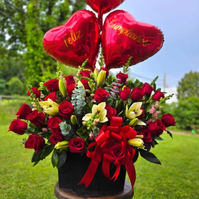 Red rose arrangement with heart balloons and a red ribbon bow