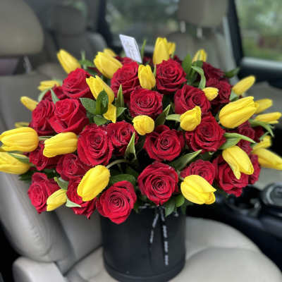 Bouquet of red roses and yellow tulips in a black hat box
