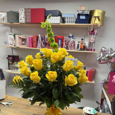 Yellow roses arranged in a glass vase with a yellow ribbon.