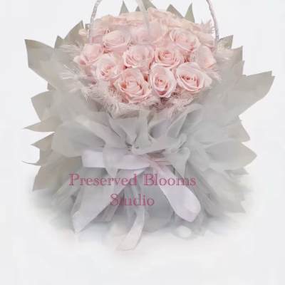 Round basket of pale pink roses wrapped in soft gray tulle with a ribbon handle