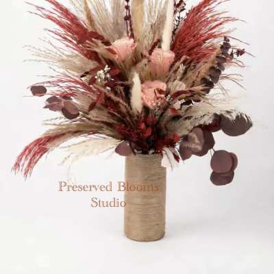 Tall dried arrangement with peach roses, red and tan pampas plumes in a twine-wrapped cylinder vase