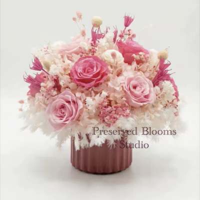 Low pink and white preserved flower arrangement with roses in a mauve ceramic pot