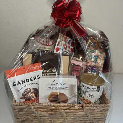Gift basket of assorted snacks and sweets wrapped in clear cellophane with a red bow