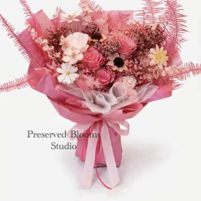 Pink bouquet of roses and daisies wrapped in pink paper with matching ribbons