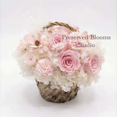 Pink and white roses arranged in a small woven basket.